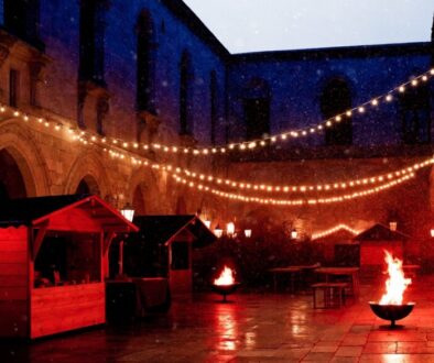 Adventmarkt im Innenhof der Kartause Gaming mit Lichterketten, Marktständen und Feuerschalen im Schnee