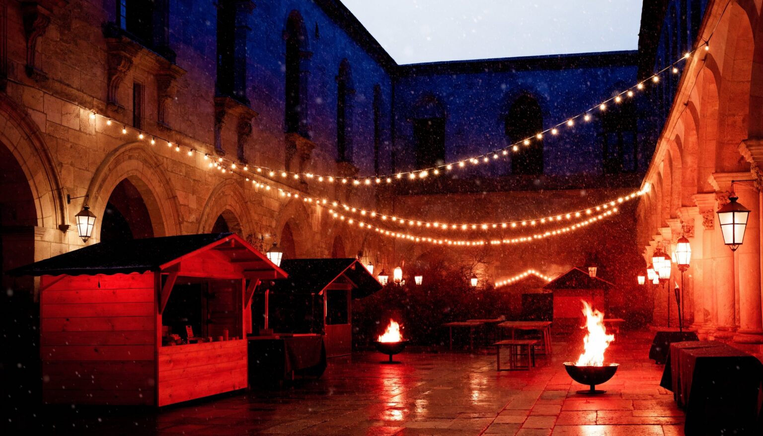 Adventmarkt im Innenhof der Kartause Gaming mit Lichterketten, Marktständen und Feuerschalen im Schnee