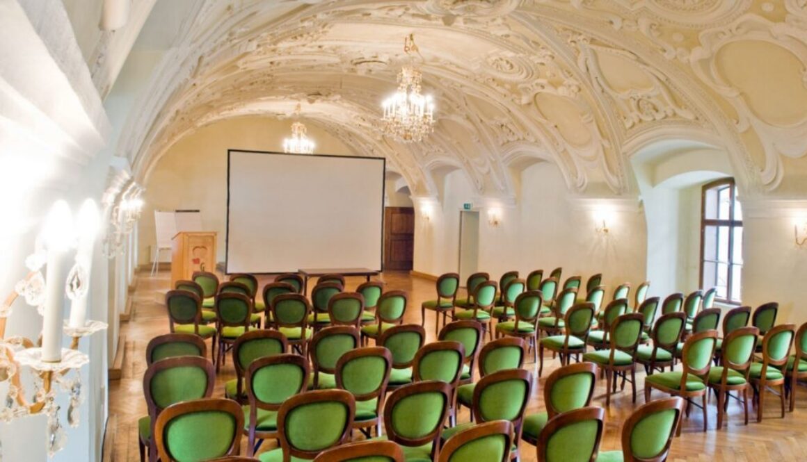 Barocker Seminarsaal mit Stuckdecke, Kronleuchtern und Bestuhlung mit Leinwand für Seminare und Teamtage in der Kartause Gaming