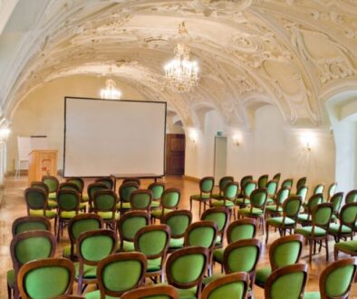 Barocker Seminarsaal mit Stuckdecke, Kronleuchtern und Bestuhlung mit Leinwand für Seminare und Teamtage in der Kartause Gaming