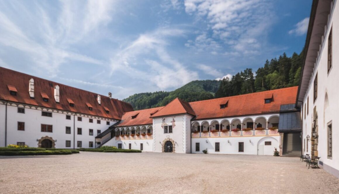 Prälatenhof der Kartause Gaming – ruhiger Klosterhof mit Arkaden, weiße Fassaden und rote Dächer vor bewaldeten Bergen
