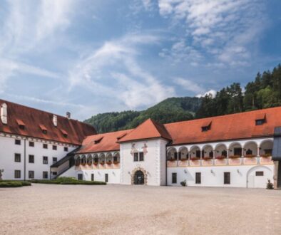Prälatenhof der Kartause Gaming – ruhiger Klosterhof mit Arkaden, weiße Fassaden und rote Dächer vor bewaldeten Bergen