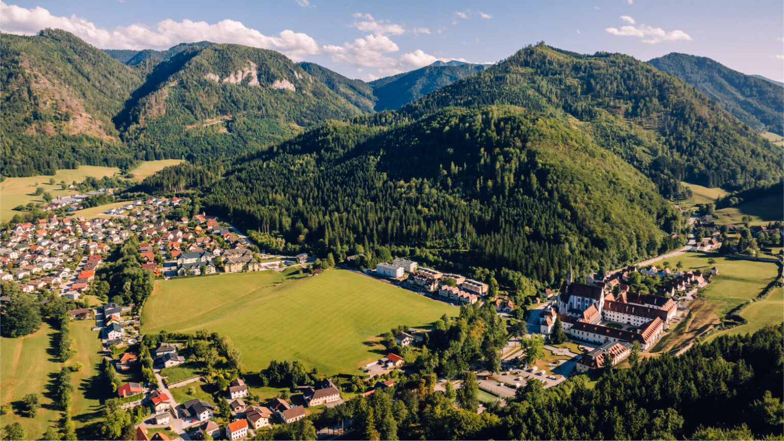 Gaming in Niederösterreich von oben: Ort im Tal mit der Kartause und den bewaldeten Voralpen